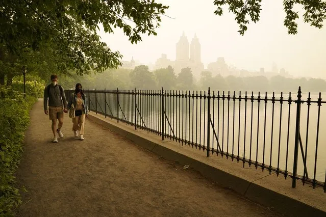 People walk in Central Park as smoke from wildfires in Canada cause hazy conditions in New York City on June 7, 2023. Smoke from Canada's wildfires has engulfed the Northeast and Mid-Atlantic regions of the US, raising concerns over the harms of persistent poor air quality. (Photo by Timothy A. Clary/AFP Photo)