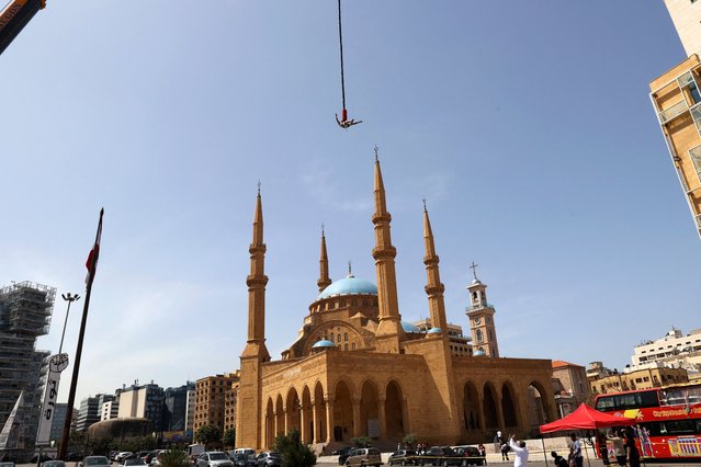 A picture taken on April 23, 2023, shows a man bungee jumping from a crane at Martyrs Square in Beirut. (Photo by Anwar Amro/AFP Photo)