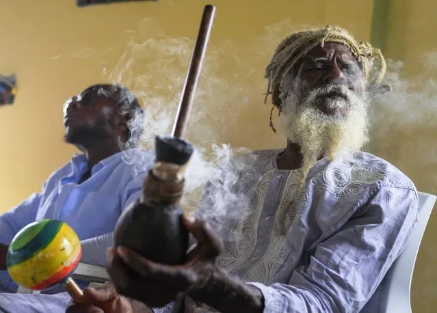 Ras Jah, a member of the Ras Freeman Foundation for the Unification of Rastafari, prepares to pass a chalice pipe with marijuana to the left during service in the tabernacle on Sunday, May 14, 2023, on the Ras Freeman Foundation for the Unification of Rastafari property in Liberta, Antigua. The Rastafari faith is rooted in 1930s Jamaica, growing as a response by Black people to white colonial oppression. The beliefs are a melding of Old Testament teachings and a desire to return to Africa. (Photo by Jessie Wardarski/AP Photo)