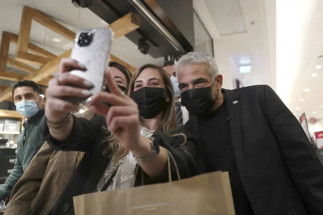 Yair Lapid, right, leader of the Yesh Atid opposition party, poses for a selfie photo with people in a shopping mall while campaigning a day before national elections in Haifa , Israel, Monday, March 22, 2021. Israelis will head to the polls on Tuesday for what will be the fourth parliamentary election in just two years. (Photo by Ariel Schalit/AP Photo)