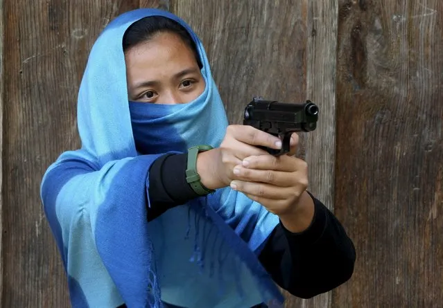 A female rebel fighter of the New People's Army (NPA) aims a pistol during an event commemorating the 47th anniversary of the founding of the Communist Party of the Philippines, in Ifugao province, north of Manila December 29, 2015. (Photo by Harley Palangchao/Reuters)