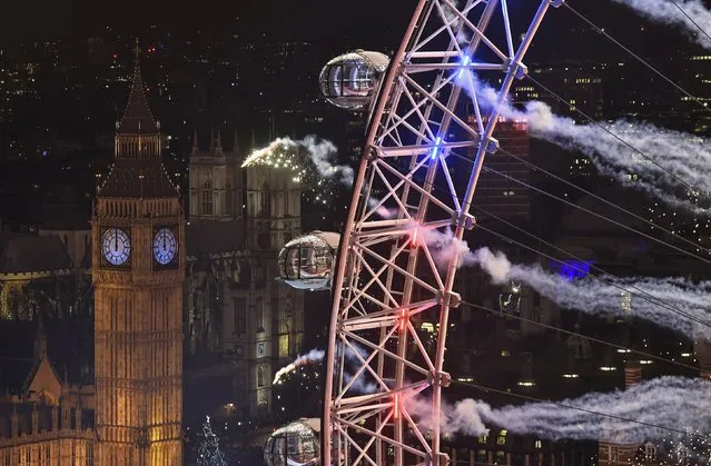 Fireworks explode around the London Eye wheel, the Big Ben clock tower and the Houses of Parliament to mark the beginning of the New Year in London, Britain, January 1, 2016. (Photo by Toby Melville/Reuters)