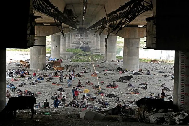 Homeless people take rest under a bridge to get respite from the heat on a hot summer afternoon in New Delhi on May 11, 2022. (Photo by Sajjad Hussain/AFP Photo)