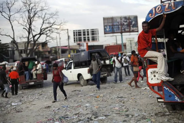 People walk near transportation pick-up trucks called “Tap Tap” at a station in Petion Vile in Port-au-Prince February 6, 2015. (Photo by Andres Martinez Casares/Reuters)
