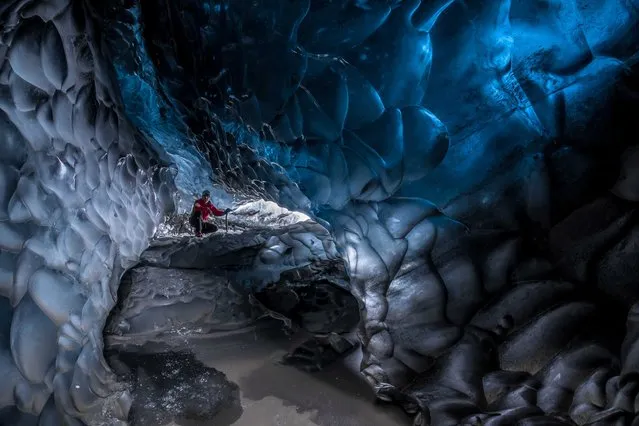 Stunning images have revealed ice-cool British tourists chilling out inside Europe’s largest glacier – despite being at risk of flooding. The spectacular collection of images show the explorers braving the freezing temperatures to climb, photograph and even abseil down the inside of the icy cliff sides. Another image shows one visitor on his knees appearing to pray next to a water fall of melted ice. Other glistening shots show an adventurer trying to keep warm by a fire whose flames dance beautifully against the glossy roof. More shots show the caves sparkling like crystal with one ice formation appearing to resemble bubble wrap. In one picture, a brave tourist stands at the edge of a river flowing through the centre of the frosty caves. (Photo by Einar Runar Sigurdsson/Mediadrumworld.com)