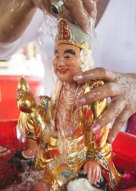 A Balinese woman cleans a statue ahead of the upcoming Chinese New Year at a temple in Denpasar, Bali, Indonesia, 12 February 2015. (Photo by Made Nagi/EPA)