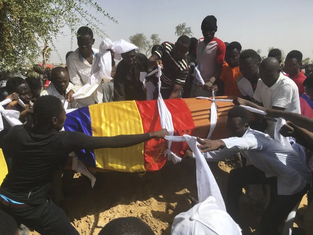 Mourners lower the coffin of one of the victims of protest who was killed this week during his funeral at a cemetery in N'Djamena, Chad, Saturday, May 1, 2021. Hundreds of chanting mourners carrying Chadian flags gathered Saturday to bury victims who were shot dead earlier this week amid demonstrations against the country's new military government. (Photo by Sunday Alamba/AP Photo)