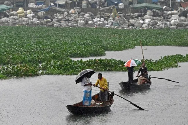 Men ride on boats as it rains in Dhaka on August 29, 2023. (Photo by Munir Uz Zaman/AFP Photo)