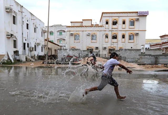 Children from a local neighbourhood play in a roadside puddle accumulated from rain brought by Cyclone Luban in Salalah, Oman, October 13, 2018. (Photo by Reuters/Stringer)