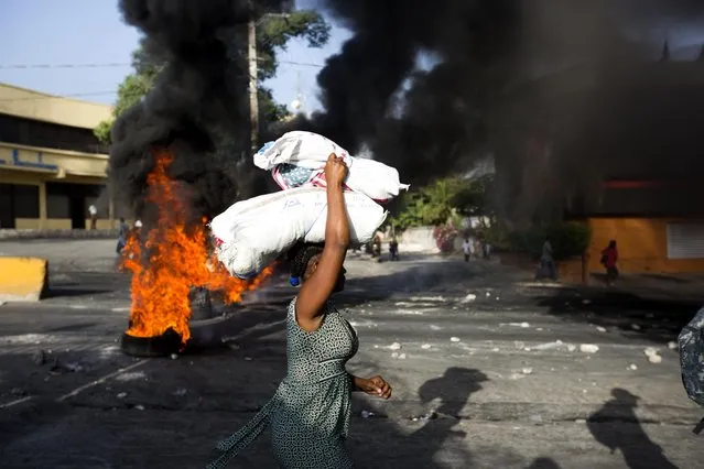 A woman carries items during a protest over the cost of fuel in Port-au-Prince, Haiti, Saturday, July 7, 2018. (Photo by Dieu Nalio Chery/AP Photo)