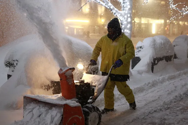 A man operates a snow blower on the sidewalks of an office building  in New York, January 23, 2016. (Photo by Gordon Donovan/Yahoo News)