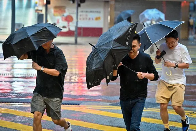 People struggle with their umbrellas in high winds brought by Super Typhoon Saola in Causeway Bay in Hong Kong on September 1, 2023. Super Typhoon Saola threatened southern China on September 1 with some of the strongest winds the region has endured, forcing the megacities of Hong Kong and Shenzhen to effectively shut down. (Photo by Mladen Antonov/AFP Photo)