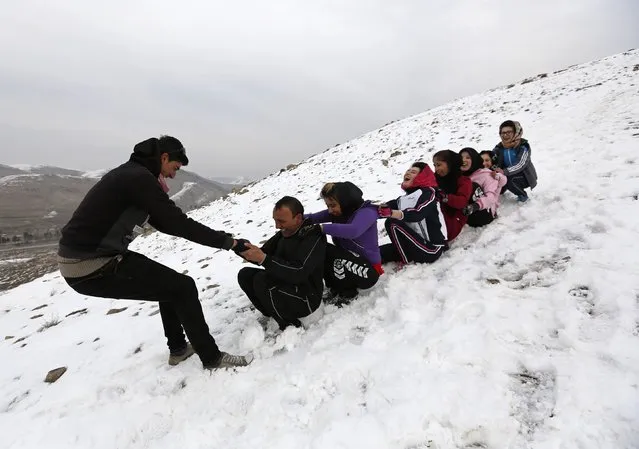 Members of Afghanistan's Women's National Cycling Team slide down a hill after exercises on a snowy mountain in Qargha on the outskirts of Kabul March  9, 2015. (Photo by Mohammad Ismail/Reuters)