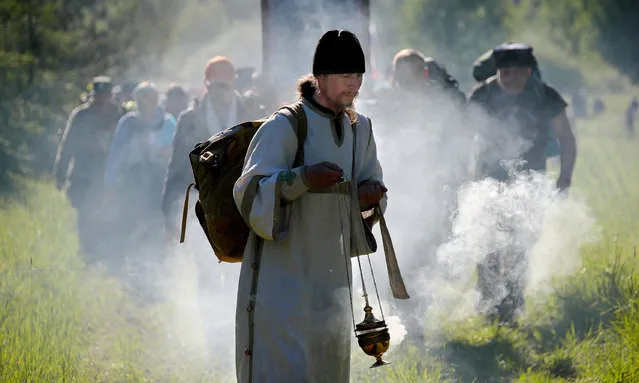 An Orthodox priest leads pilgrims in the Velikoretsky procession, one of the largest in Russia, annually held from June 3 to 8 to venerate the Icon of St Nicholas discovered, as legend has it, on the bank of the Velikaya River in the 14th century in Kirov Region, Russia on June 5, 2021. The route reaching from Kirov to the village of Velikoretskoye and back measures a total of 150km and attracts thousands of believers. (Photo by Dmitry Feoktistov/TASS)