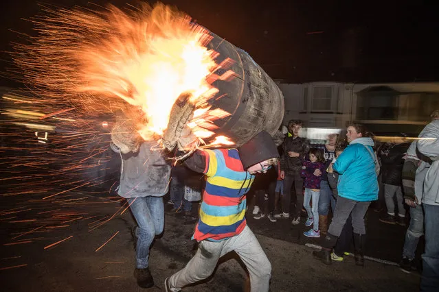 A participant runs with a burning barrel soaked in tar at the annual Ottery St Mary tar barrel festival on November 5, 2018 in Devon, England. The tradition, which is over 400 years old, sees competitors (who must have been born in the town to take part) running with burning barrels on their backs through the village, until the heat becomes too unbearable or the barrel breaks down, starting with junior barrels carried by children and continuing all evening with ever larger and larger barrels. The event, which has been threatened with closure on previous years due to increasing public liability insurance costs, raises thousands of pounds for charity and attracts spectators from around the world. (Photo by Matt Cardy/Getty Images)