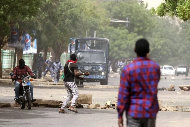A man throws a stone towards police during a protest over economic conditions, in Khartoum, Sudan, Wednesday, June 30, 2021. The World Bank and the International Monetary Fund said in a joint statement Tuesday, that Sudan has met the initial criteria for over $50 billion in foreign debt relief, another step for the East African nation to rejoin the international community after nearly three decades of isolation. (Photo by Marwan Ali/AP Photo)
