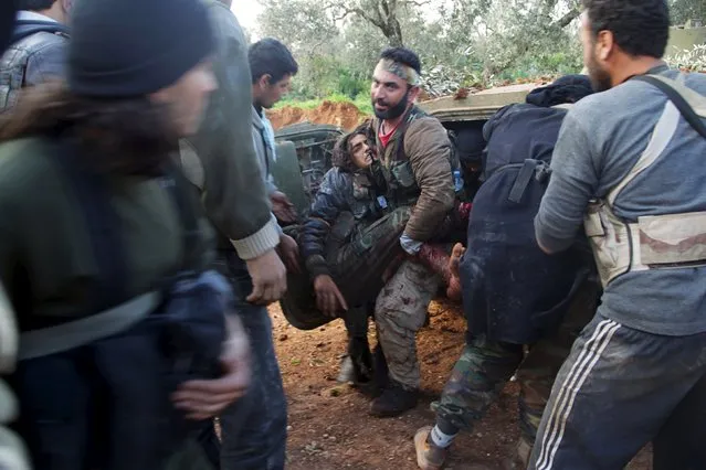 Rebel fighters from the Ahrar al-Sham Islamic Movement help an injured fellow fighter during what they said was an offensive to take the northwestern city of Idlib March 24, 2015. (Photo by Khalil Ashawi/Reuters)