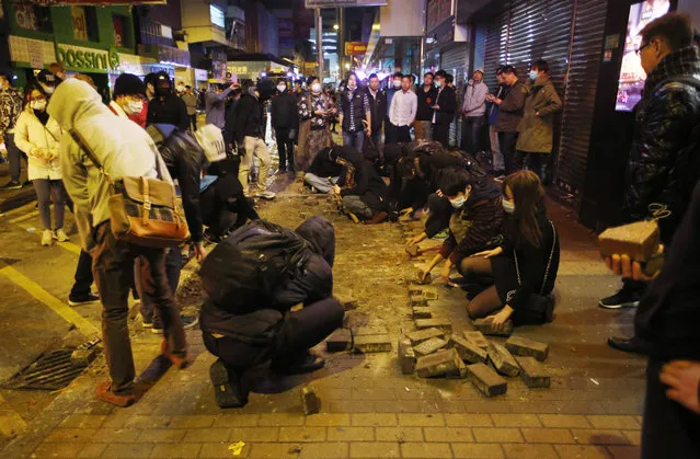 Protesters collect bricks from a pathway during clashes with police in Mong Kok district of Hong Kong, Tuesday, February 9, 2016. (Photo by Kin Cheung/AP Photo)