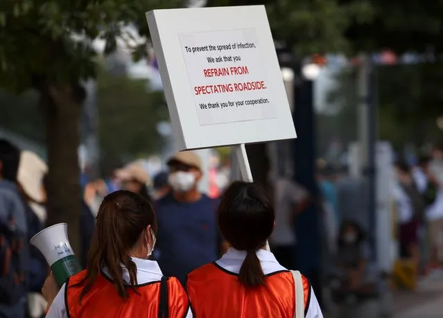 Staff members display a sign asking members of the public to refrain from spectating on the roadside, during the men's triathlon at Odaiba Marine Park in Tokyo, Japan, July 26, 2021. (Photo by Issei Kato/Reuters)