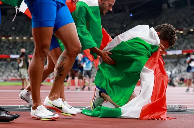 (L to R) Italy's Lorenzo Patta and Italy's Filippo Tortu celebrate with the national flag after winning the gold medal in the men's 4x100m relay final during the Tokyo 2020 Olympic Games at the Olympic Stadium in Tokyo on August 6, 2021. (Photo by Kai Pfaffenbach/Reuters)