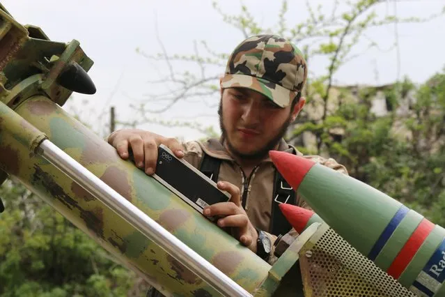A rebel fighter of al-Jabha al-Shamiya (the Shamiya Front) uses a level tool on a new locally made cannon named “al-Qannas” (Sniper), before launching it towards forces loyal to Syria's President Bashar al-Assad stationed in Hanano barracks in Aleppo April 8, 2015. (Photo by Abdalrhman Ismail/Reuters)