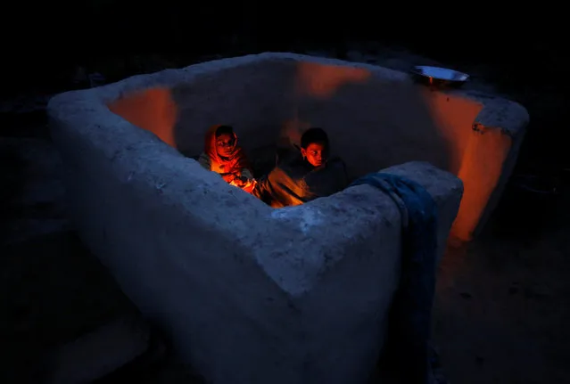 Children of a snake charmer prepare dinner outside their home in Jogi Dera (snake charmers settlement), in the village of Baghpur, in the central state of Uttar Pradesh, India January 16, 2017. An ancient tribe of snake charmers, known as Saperas, have thrived over the generations by catching venomous snakes and making them dance to their music. Snakes are revered by Hindus in India and snake charmers are considered the followers of Lord Shiva, the blue-skinned Hindu god who is usually portrayed wearing a king cobra around his neck. Snake charmers were once a regular fixture at Indian bazaars and festivals, mesmerising crowds of onlookers with their ability to control some of the world's most venomous creatures. They would often be the main source of medicines if someone suffered from a snake bite. The snake charmers of Jogi Dera say their centuries-old tradition is slowly dying out as authorities seek to enforce wildlife protection laws, and after an outright ban on the practice in 1991. (Photo by Adnan Abidi/Reuters)