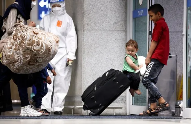 A child is pushed on a suitcase as Afghan evacuees who supported the South Korean government's activities in Afghanistan arrive at Incheon International Airport in Incheon, South Korea, August 26, 2021. (Photo by Kim Hong-Ji/Reuters)