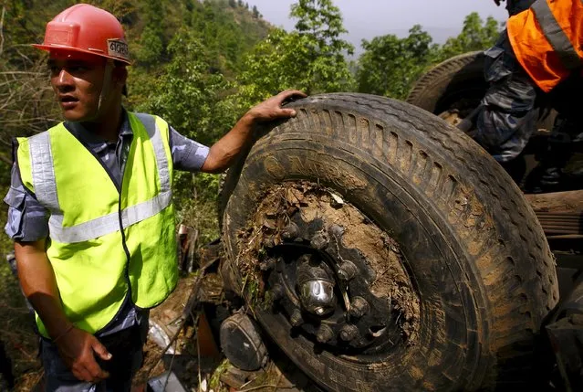 A rescue team member stands next to the wreckage of a bus while recovering the bodies of the victims at Jayaprekhola in Dhading district, on the outskirts of Kathmandu, Nepal April 22, 2015. A bus with an Indian number plate carrying Indian pilgrims fell around 200 meters down the hill from the Prithivi Highway and 16 Indian pilgrims were killed, according to local media. (Photo by Navesh Chitrakar/Reuters)