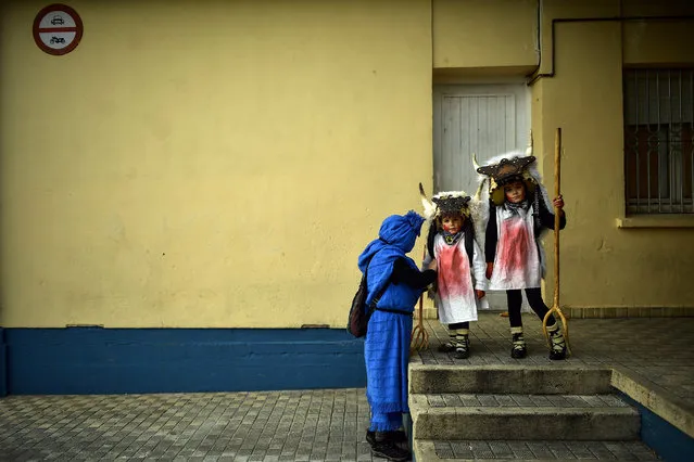 Young “Momotxorros” prepare to take part in the carnival wearing typical carnival dress, in Alsasua, northern Spain, Tuesday, March 5, 2019. During the carnival Momotxorros, characters who seem to have been resurrected from a prehistoric ritual, come out onto the streets wearing horns and hiding their faces under headscarves, and dressed in a white sheet stained with blood. (Photo by Alvaro Barrientos/AP Photo)