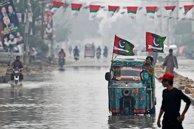 An auto rickshaw with Pakistan Peoples Party (PPP) flags make its way through a flooded street in Karachi on February 4, 2024, ahead of the upcoming general elections. (Photo by Asif Hassan/AFP Photo)