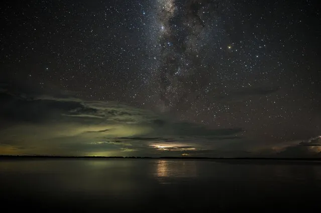 View of the milky way in the night sky as a lightning strikes over lake Maracaibo in the village of Ologa, in Zulia state, Venezuela, on September 6, 2021. (Photo by Federico Parra/AFP Photo)