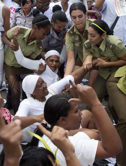 Policewomen drag away members of Ladies in White, a women's dissident group that calls for the release of political prisoners, during their weekly protest in Havana, Cuba, Sunday, March 20, 2016. (Photo by Rebecca Blackwell/AP Photo)