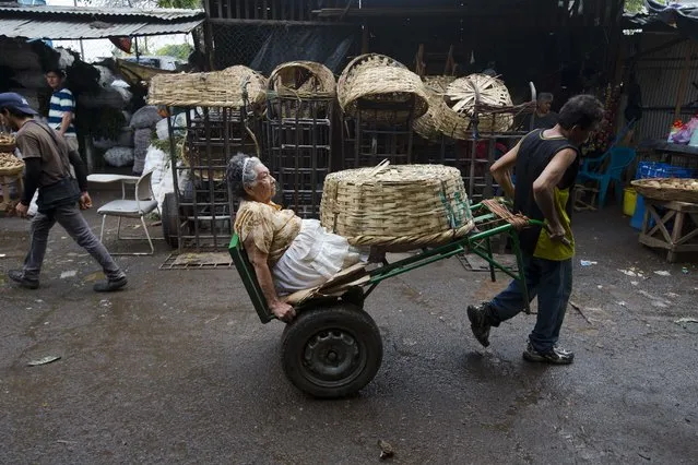 Vendor Carmen Diaz, 84, is pulled by a market porter as she makes her way home at the end of her work day in the Oriental Market in Managua, Nicaragua, late Thursday, April 30, 2015. Known as “Chanita”, Diaz has worked since she was 8-years-old at the market, where she sells a hodgepodge of household items that include small piggy banks, coat hooks and liquid cleaners. (Photo by Esteban Felix/AP Photo)