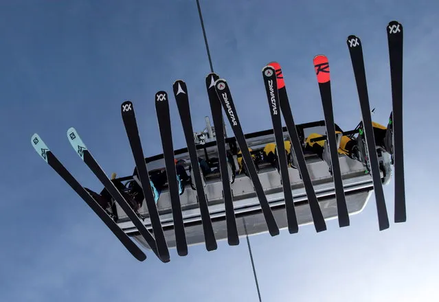 Skiers sit in a chairlift during the winter season opening day at Germany's highest mountain, the Zugspitze, in Grainau, near Garmisch-Partenkirchen, Germany, November 19, 2021. (Photo by Lukas Barth/Reuters)