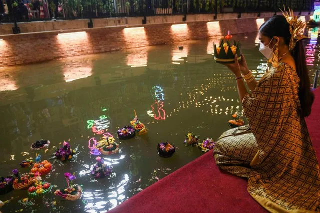 A woman wearing a face mask to prevent the spread of the coronavirus disease (COVID-19), gather to place krathongs (floating baskets) into a canal during the Loy Krathong festival, which is held as a symbolic apology to the goddess of the river in Bangkok, Thailand, November 19, 2021. (Photo by Chalinee Thirasupa/Reuters)