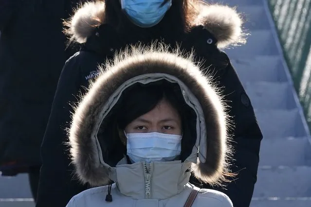 A woman wearing a mask and covered up for cold weather braves a cold front in Beijing, China, Monday, November 22, 2021. (Photo by Ng Han Guan/AP Photo)