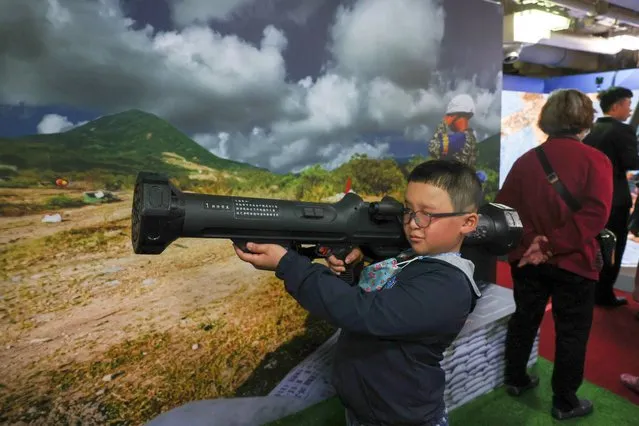 A child poses for a photo while holding a javelin missile that is on display on a Panshih-class fast combat support ship in Keelung, Taiwan on March 17, 2024. (Photo by Ann Wang/Reuters)
