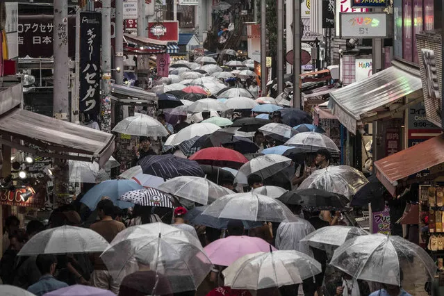 Shoppers with umbrellas walk along the Takeshita Street Friday, June 7, 2019, in the Harajuku district of Tokyo. Harajuku is one of the most popular shopping neighborhoods in Tokyo. (Photo by Jae C. Hong/AP Photo)