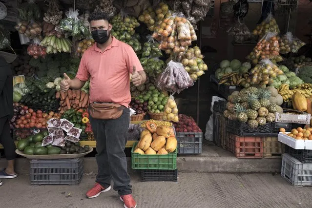 A vegetable vendor flashes two thumbs up in the Kennedy neighborhood of Tegucigalpa, Honduras, Friday, November 26, 2021. (Photo by Moises Castillo/AP Photo)
