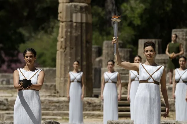 High priestess Actress Katerina Lehou, right, rises a torch as a priestess holds a pot with the Olympic Flame, during the final dress rehearsal of the lighting of the Olympic flame at Ancient Olympia, in western Greece on Wednesday, April 20, 2016. (Photo by Petros Giannakouris/AP Photo)