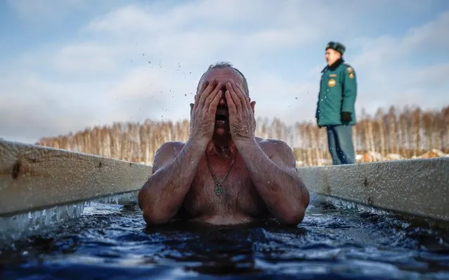 A man immerses himself in the icy waters during celebrations of the Orthodox Christian feast of Epiphany in the settlement of Ivanovskoye in the Moscow region, Russia on January 19, 2022. (Photo by Maxim Shemetov/Reuters)