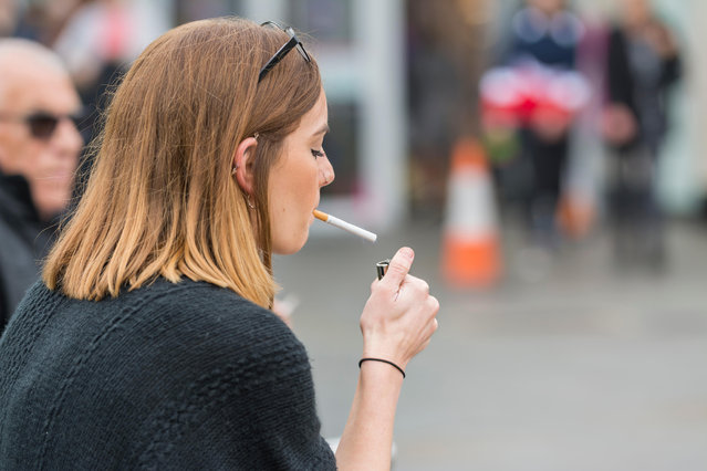 Young Caucasian woman lighting a cigarette in the United Kingdom. Unhealthy lifestyle. (Photo by Alamy Stock Photo)