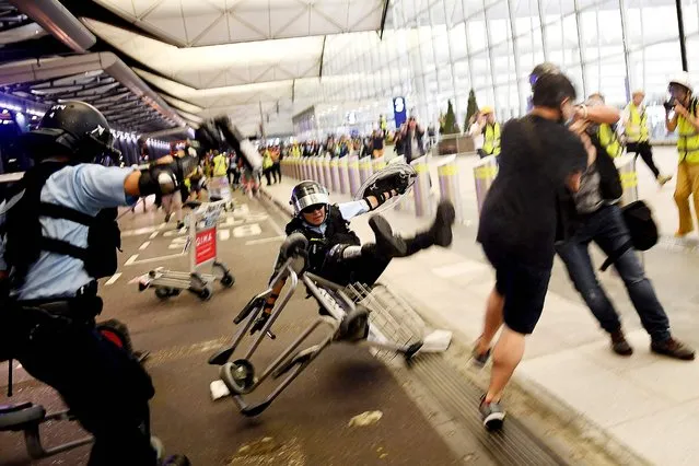A Hong Kong policeman (C) falls backwards as they scuffle with pro-democracy protesters during ongoing demonstrations at Hong Kong's International Airport on August 13, 2019. Hundreds of flights were cancelled or suspended at Hong Kong's airport on August 13 as pro-democracy protesters staged a second disruptive sit-in at the sprawling complex, defying warnings from the city's leader who said they were heading down a “path of no return”. (Photo by Manan Vatsyayana/AFP Photo)