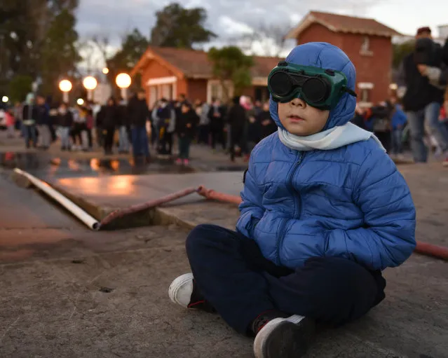 A bundled up youth wears special glasses to watch a total solar eclipse in Chascomus, Argentina, Tuesday, July 2, 2019. A solar eclipse occurs when the moon passes between the Earth and the sun and scores a bull's-eye by completely blocking out the sunlight. (Photo by Gustavo Garello/AP Photo)