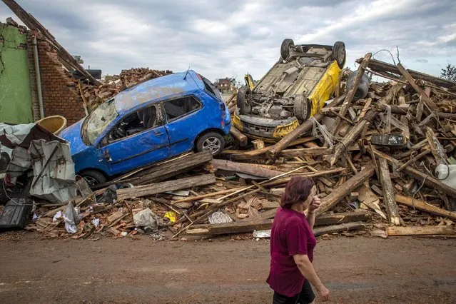 A woman walks past damaged cars after a tornado hit in Mikulcice, Czech Republic, 25 June 2021. A rare tornado on 24 June evening swept through the region of South Moravia, in south-eastern Czech Republic, leaving thousands of houses destroyed and damaged, authorities announced. At least three people died, according to a spokesperson of the regional ambulance service. (Photo by Martin Divisek/EPA/EFE)