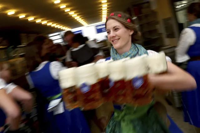 A waitress holds glasses of beer during the opening of the 186th “Oktoberfest” beer festival in Munich, Germany, Saturday, September 21, 2019. (Photo by Matthias Schrader/AP Photo)