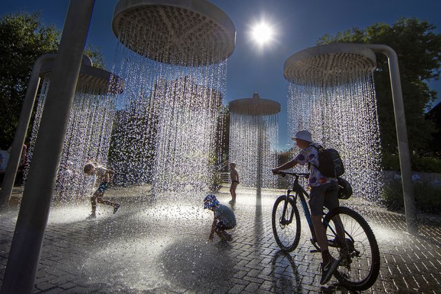 Children cool off in a public fountain in Vilnius, Lithuania, Thursday, June 27, 2024. A heat wave continues in Lithuania as temperatures rise to a high of 32 degrees Celsius (89.6 degrees Fahrenheit). (Photo by Mindaugas Kulbis/AP Photo)