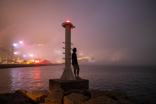 A man stands on a jetty on the fog-shrouded Victoria Harbour Wanchai in Hong Kong, China, 22 March 2022. Fog is common in Hong Kong in spr​ingtime when the territory is affected by alternate cold and warm air. (Photo by Jerome Favre/EPA/EFE)