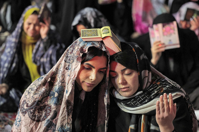 Women devotees gather to attend the ritual prayers for Laylat al-Qadr (Night of Destiny), one of the holiest nights during the Muslim fasting month of Ramadan, outside the Imamzadeh Saleh mosque in Tehran, on April 10, 2023. (Photo by Atta Kenare/AFP Photo)