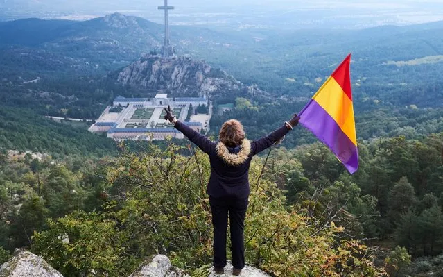 A woman flies a republican flag on top of a hill as she waits for the exhumation of former Spanish dictator Francisco Franco on October 24, 2019 in Madrid, Spain. Francisco Franco, Spain's fascist dictator, who died in 1975, is being exhumed from his purpose built mausoleum, the Valley of the Fallen. His remains are being transferred to the crypt in Mingorrubio state cemetery where his wife is buried. (Photo by Xaume Olleros/Getty Images)